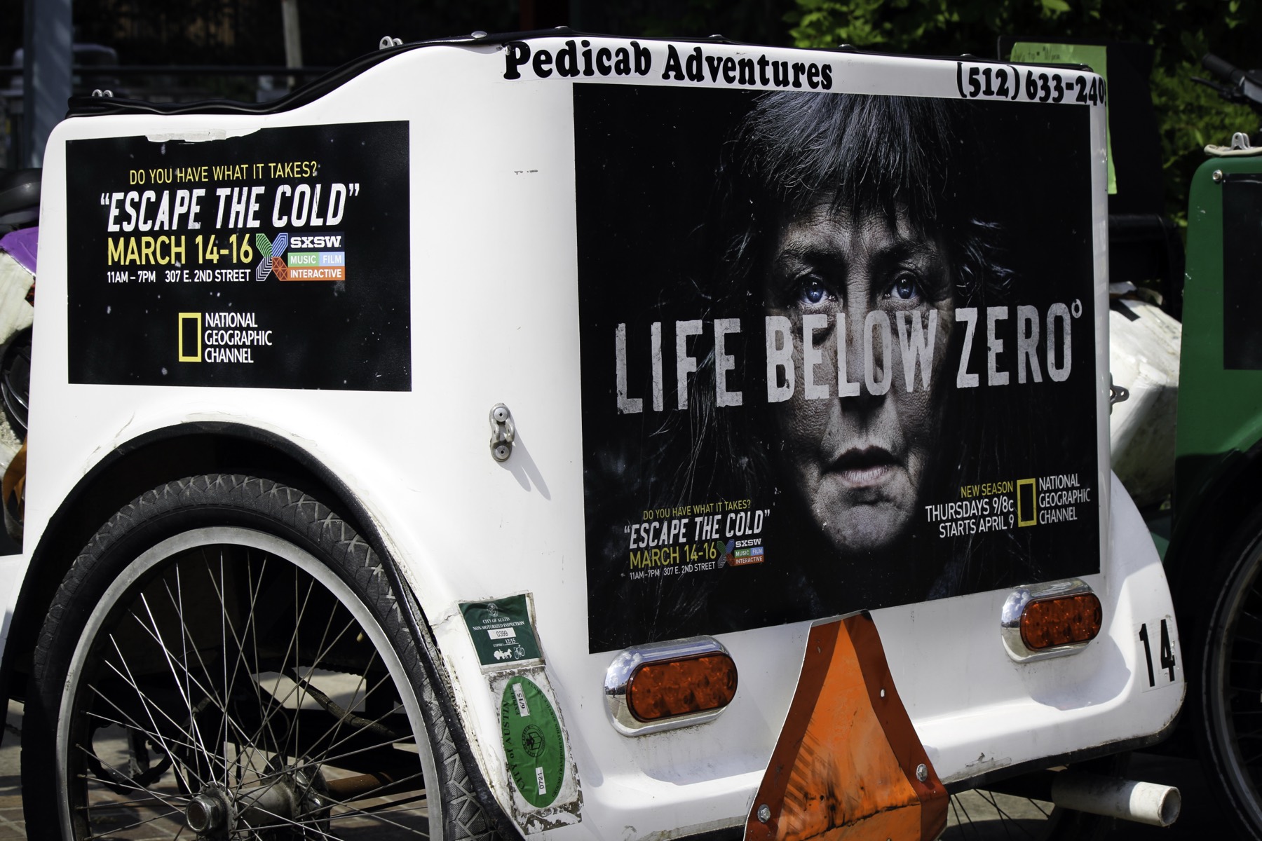A Pedicab Adventures carriage wrapped in a National Geographic Life Below Zero campaign for SXSW, with the company name and phone number lettered across the top